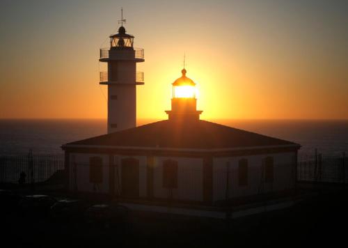 two lighthouses on top of a building at sunset at Hotel Rural Casa Fontequeiroso in Muxia