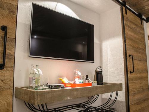 a flat screen tv on a wall with a shelf at NEhotel Nueva Estancia in León