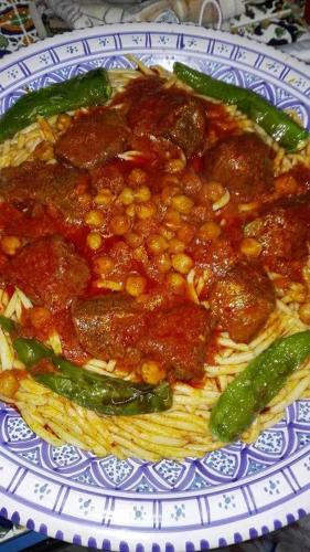 a plate of spaghetti with meatballs and green peppers at Dar El Kasba Riad Guest House in Bizerte