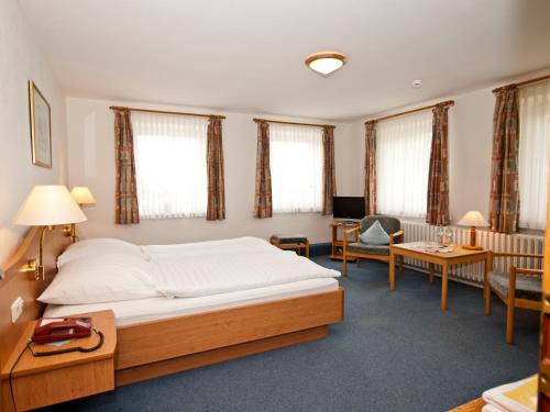a bedroom with a bed and a desk and a chair at Flair Landhotel Strengliner Mühle in Pronstorf