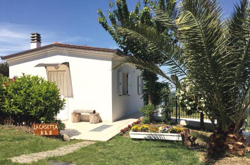 uma casa branca com uma palmeira em frente em La Casetta em Tavullia