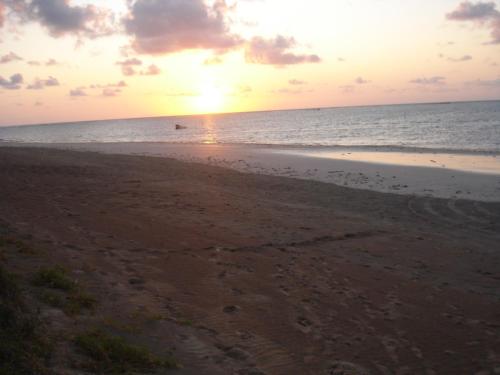 a sunset on a beach with the ocean at Pousada Riacho dos Milagres in São Miguel dos Milagres