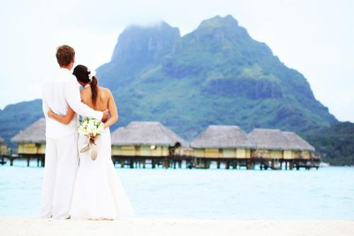 a bride and groom standing on the beach at Le Bora Bora by Pearl Resorts in Bora Bora