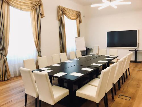 a conference room with a black table and white chairs at Hotel Panství Dlouhá Lhota in Dlouhá Lhota