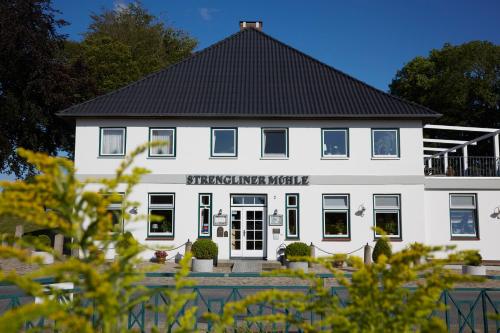 a white building with a black roof at Flair Landhotel Strengliner Mühle in Pronstorf