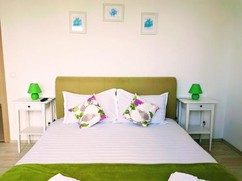 a bed with white and green sheets and pillows at Apartments For You in Olimp