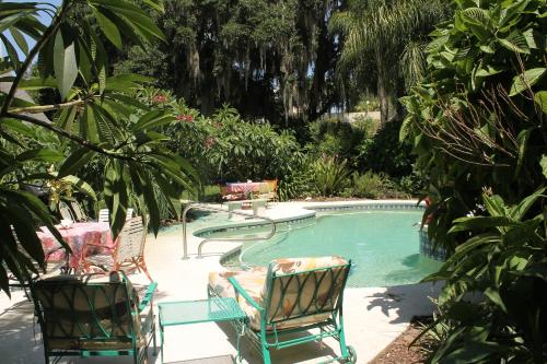 uma piscina com duas cadeiras e uma mesa e uma mesa e cadeiras em Heron Cay Lakeview Bed & Breakfast em Mount Dora