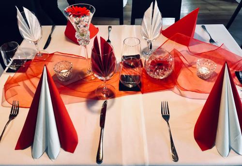 a white table with red napkins and forks and wine glasses at Hotel Panství Dlouhá Lhota in Dlouhá Lhota