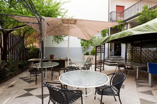 a patio with tables and chairs and an umbrella at Hotel Letizia in Orte