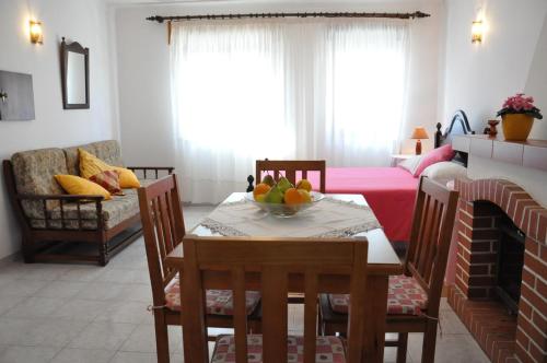 una sala de estar con una mesa con un bol de fruta. en Apartamentos Campos 0 en Porto Covo