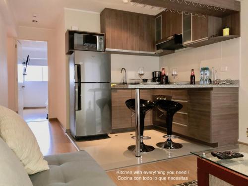 a kitchen with a stainless steel refrigerator and black stools at ALU Apartments - Limit with Miraflores Panoramic City View in Lima