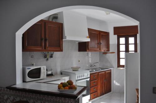 an archway in a kitchen with a bowl of fruit on the counter at Apartamentos Campos 1 in Porto Covo