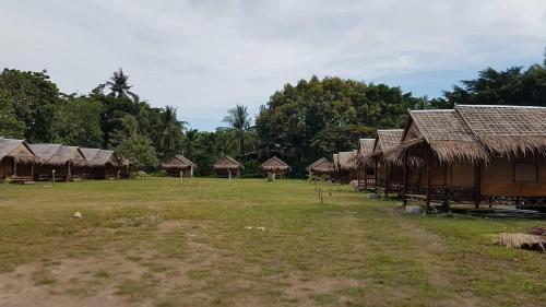 a row of huts with straw roofs in a field at Lanta Local Hut in Ko Lanta