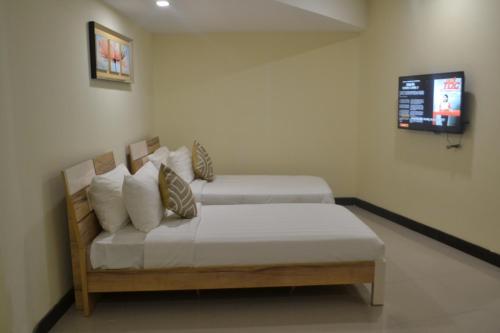 a bedroom with two beds and a tv on the wall at My Inn Hotel Kota Samarahan in Kota Samarahan