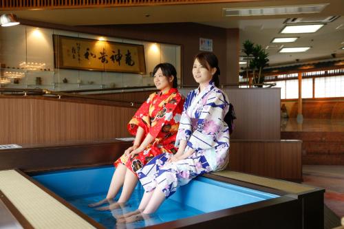 two women sitting on top of a swimming pool at Todaya in Toba