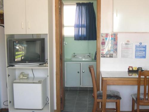 a kitchen with a table and a kitchen with a tv at Strand Motel in Tauranga