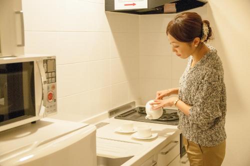a woman standing in a kitchen pouring something into a pot at Hakodate Danshaku Club Hotel & Resorts in Hakodate