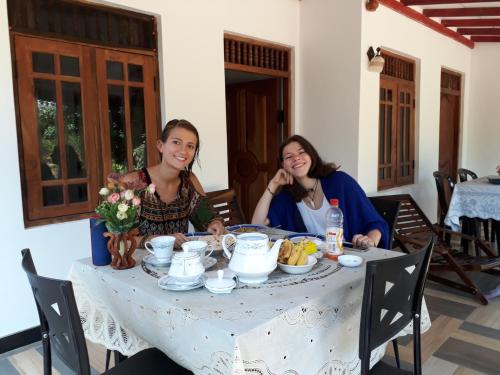 two women sitting at a table with food on it at Danara Homestay in Sigiriya