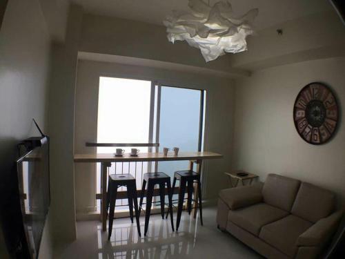 a living room with a table and chairs and a couch at AMS Staycation at Wind Residences in Tagaytay