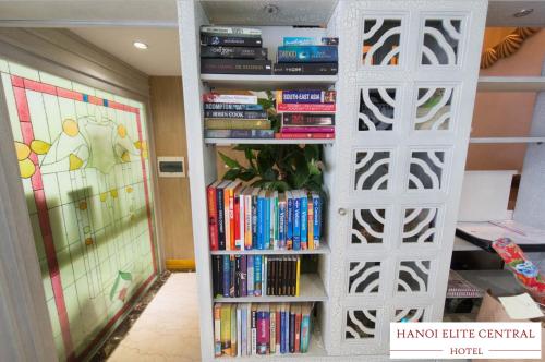 a book shelf filled with books in a room at Elite Central Hotel Hanoi in Hanoi