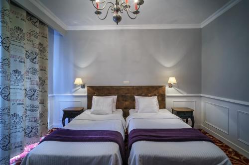 two twin beds in a room with a chandelier at Grand Częstochowa in Częstochowa