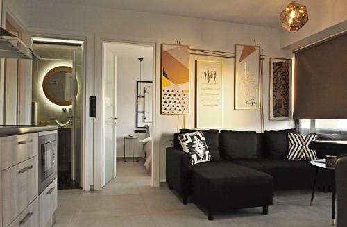 a living room with a black couch and a kitchen at The Athenians Modern Apartments in Athens