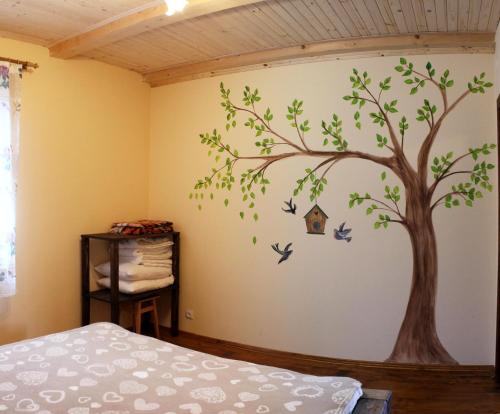 a bedroom with a tree and birds on the wall at Svit Sontsya in Turʼya Polyana