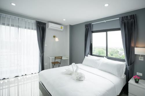 a bedroom with a large white bed with a large window at Twentynine KV Apartel in Nonthaburi