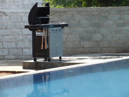 a barbecue grill sitting next to a swimming pool at Amelia Resort in Sigiriya