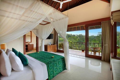 a bedroom with a bed with a green comforter at Jannata Resort and Spa in Ubud