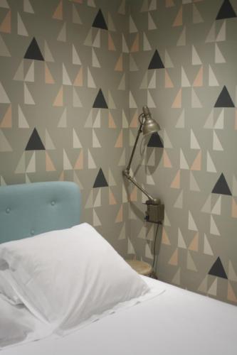 a bedroom with a bed and a lamp on a wall at La Maison de la Plage in Trouville-sur-Mer