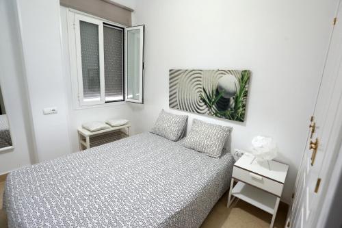 a white bedroom with a bed and two windows at Apartamento Duque de Arcos 2 in Arcos de la Frontera