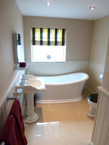 a bathroom with a tub and a sink and a window at Jockhedge Holiday Cottages in Skegness