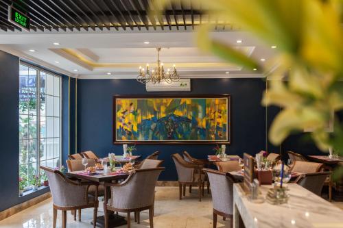 a dining room with tables and chairs and a painting on the wall at Eden Boutique Hotel & Spa in Sa Pa