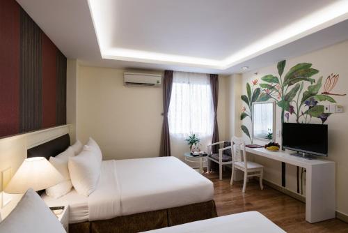 a hotel room with a white bed and a desk at Asian Ruby Center Point Hotel & Spa in Ho Chi Minh City