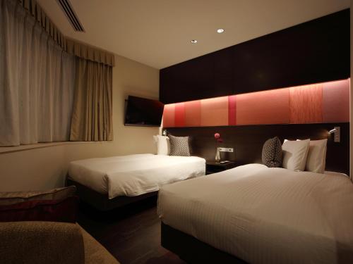 a hotel room with two beds and a couch at Red Roof Inn & Suites Osaka Namba Nipponbashi in Osaka