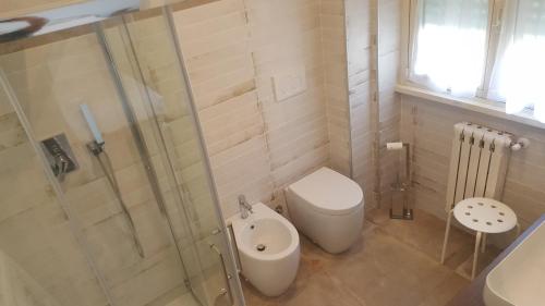 a bathroom with a toilet and a glass shower at Maison Tizi in Passoscuro