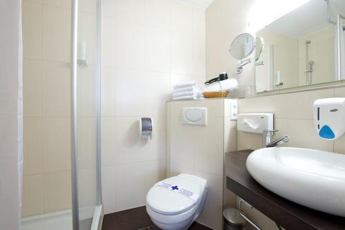 a white bathroom with a toilet and a sink at Hotel zur Riss in Biberach an der Riß