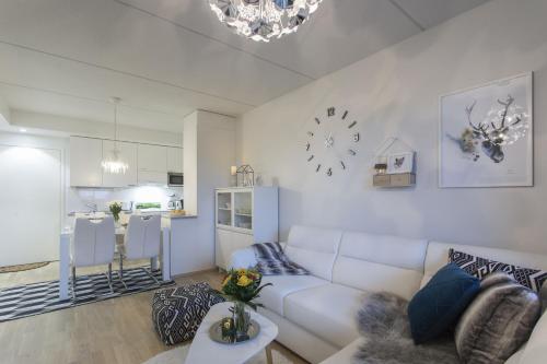 a living room with a white couch and a kitchen at Vasko Luxurious Suites, Nilo in Rovaniemi
