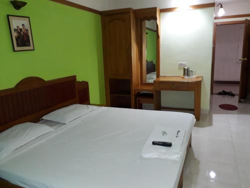 a bedroom with a bed with a remote control on it at Bennies Inn in Kottayam
