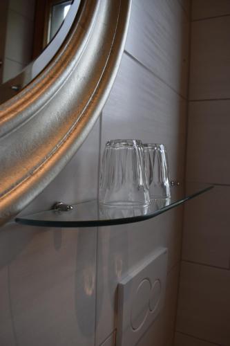 two glasses on a glass shelf under a mirror at Haus Hilgenfeld in Bad Sooden-Allendorf