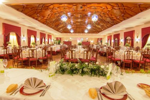 Un salón de banquetes con mesas y sillas blancas. en Hotel Carmen, en La Carlota
