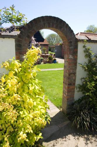 an archway in a yard with a green bush at Jockhedge Holiday Cottages in Skegness