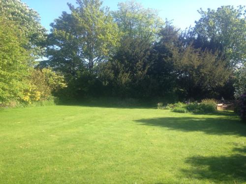 a large grass field with trees in the background at Jockhedge Holiday Cottages in Skegness