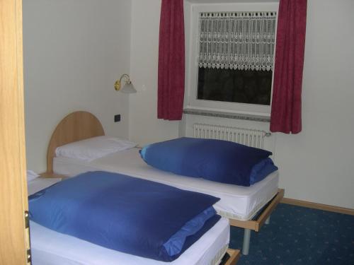 two beds in a room with a window at Cèsa Chri e Sofì in Campitello di Fassa