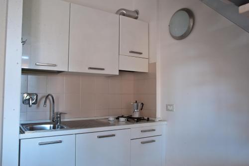 una cocina con armarios blancos y fregadero en Residence Borgomare, en Albenga