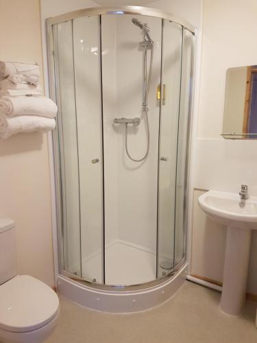 a bathroom with a shower with a toilet and a sink at The Cliff Top Inn in Bacton