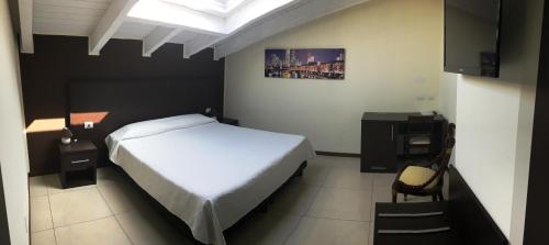 Schlafzimmer mit einem weißen Bett, einem Schreibtisch und einem Stuhl in der Unterkunft Residenza S.Event B&B in Buccinasco