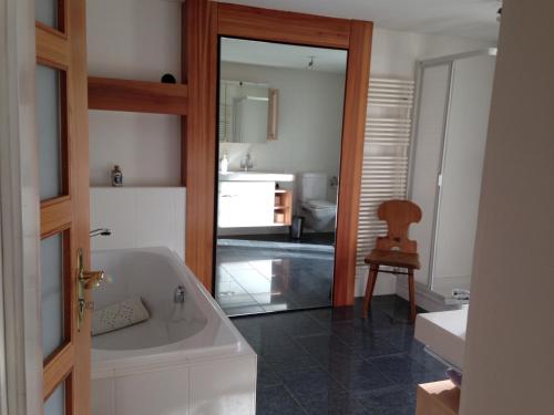 uma casa de banho com uma banheira, um lavatório e um espelho. em BnB Chantevent em Sierre