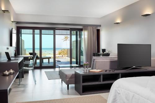 een slaapkamer met een bed en een woonkamer met een televisie bij Essenza Dune Hotel in Jericoacoara